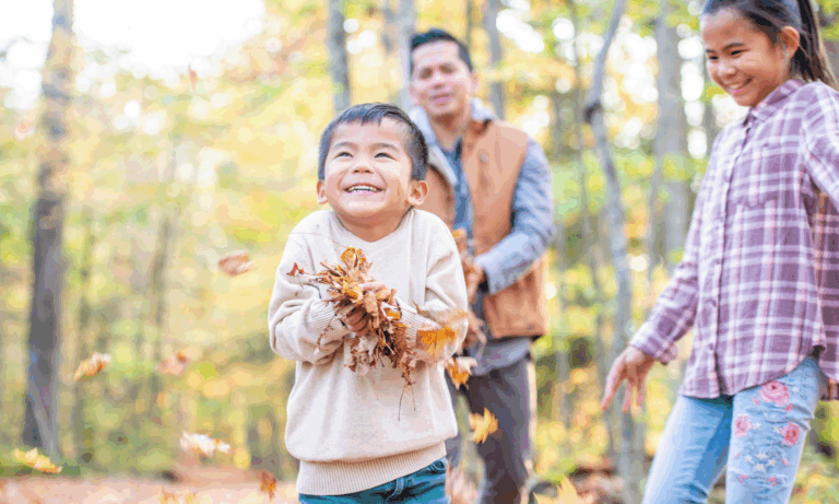 A father and kids playing in fall leaves